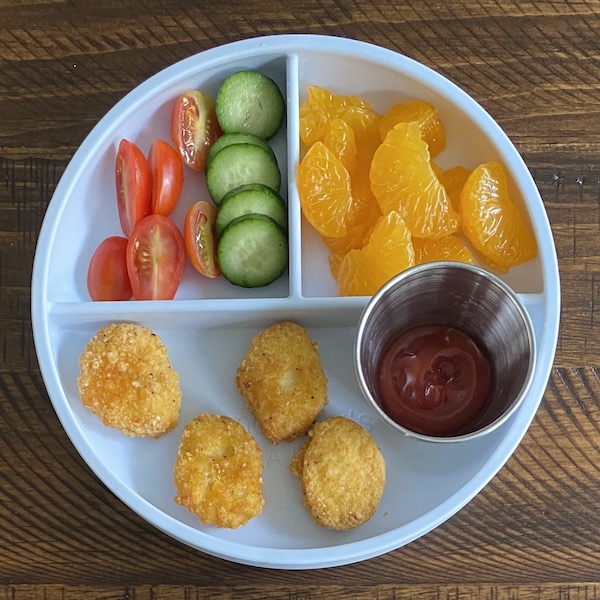 Toddler lunch with nuggets, veggies, oranges