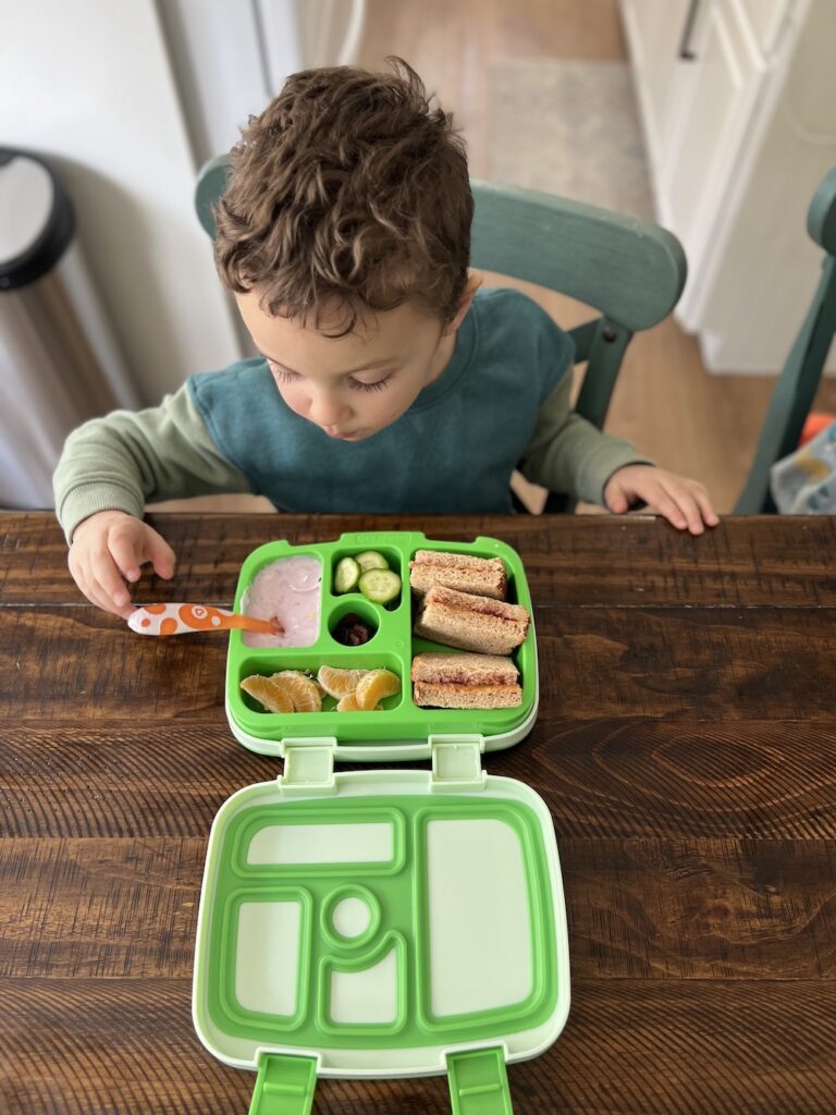 Boy eating lunch box at table.