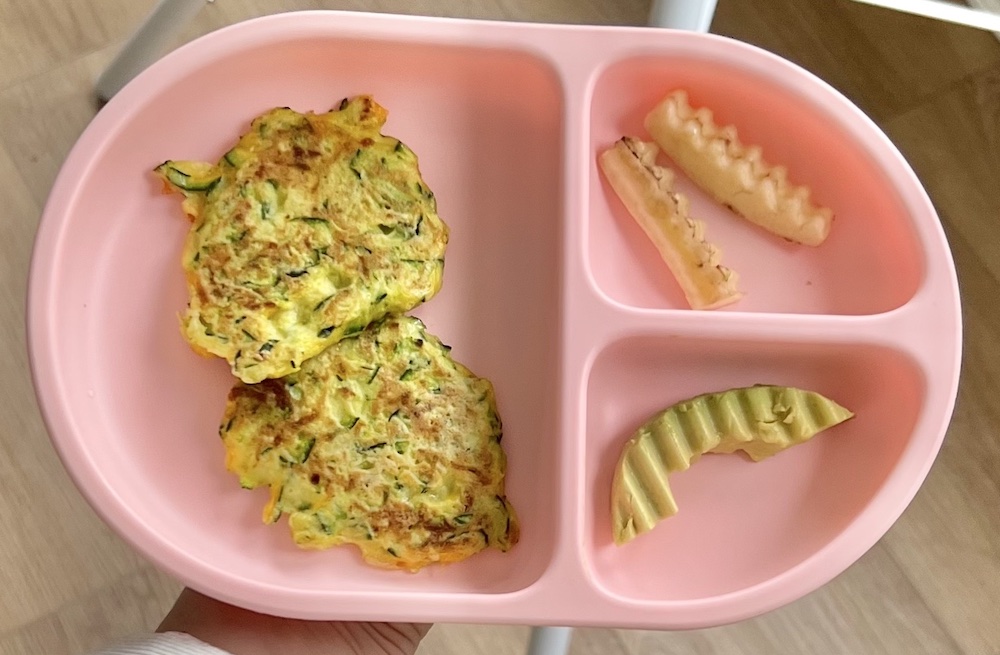 plate with zucchini fritters, banana, avocado