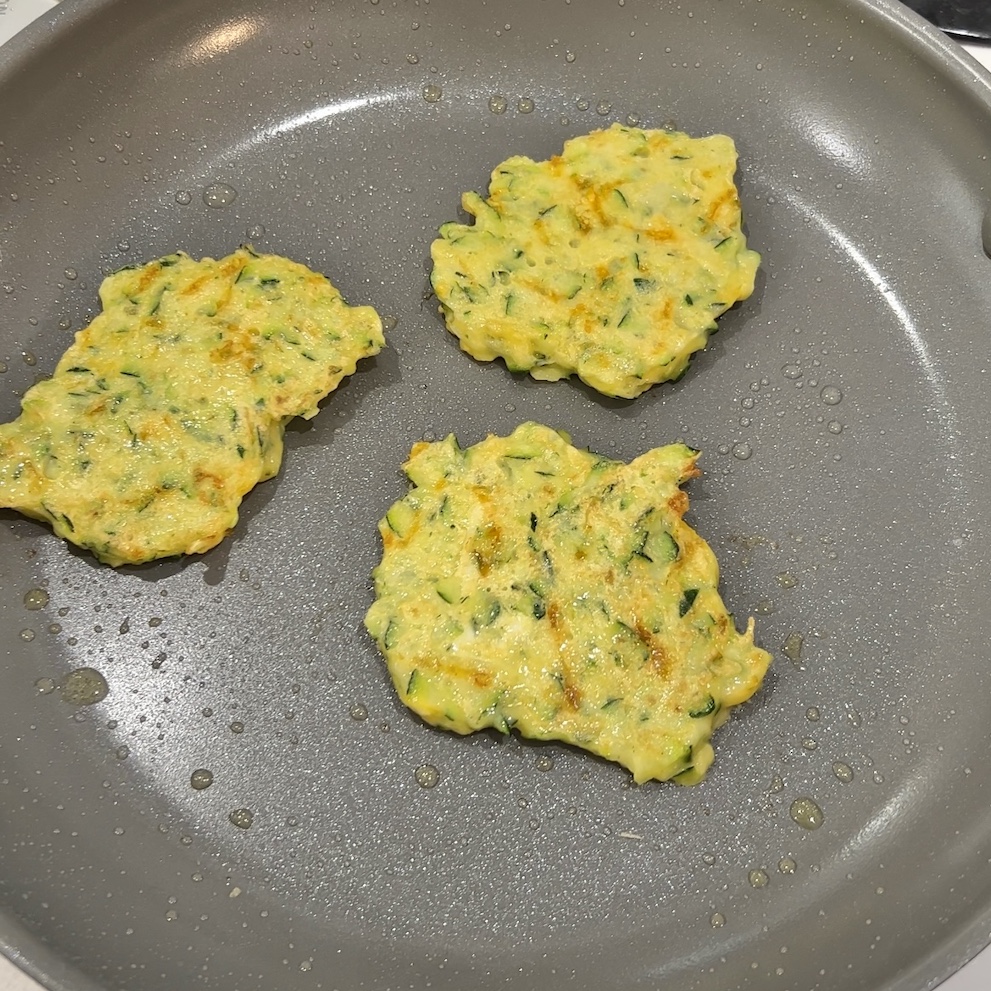 zucchini fritters cooking on pan