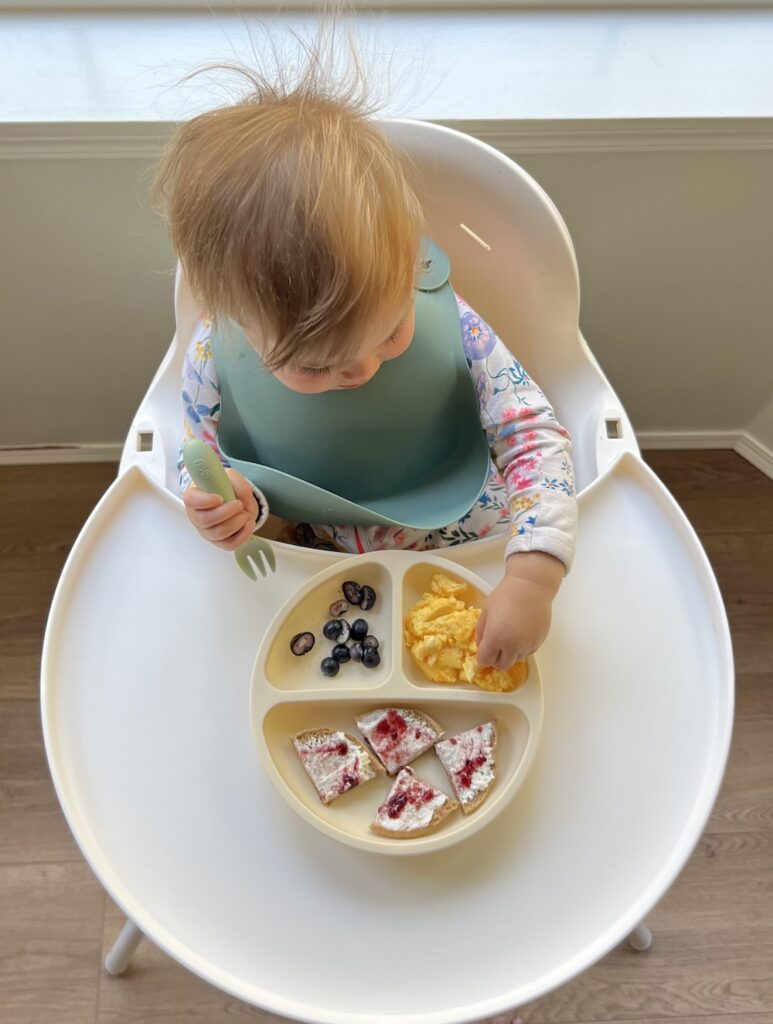 Girl sitting at high chair eating
